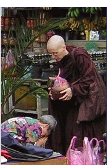 [A woman bows at Amma's feet after offering a bag of food]